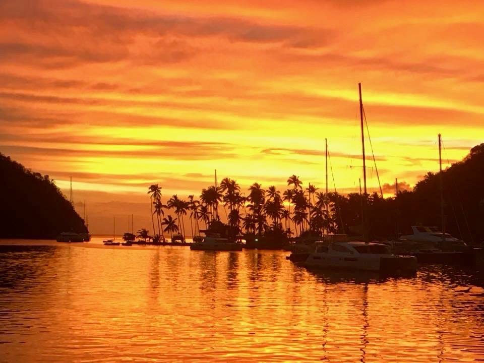 Voiliers au mouillage sous un coucher de soleil orange et doré